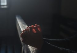 hands folded in prayer in church